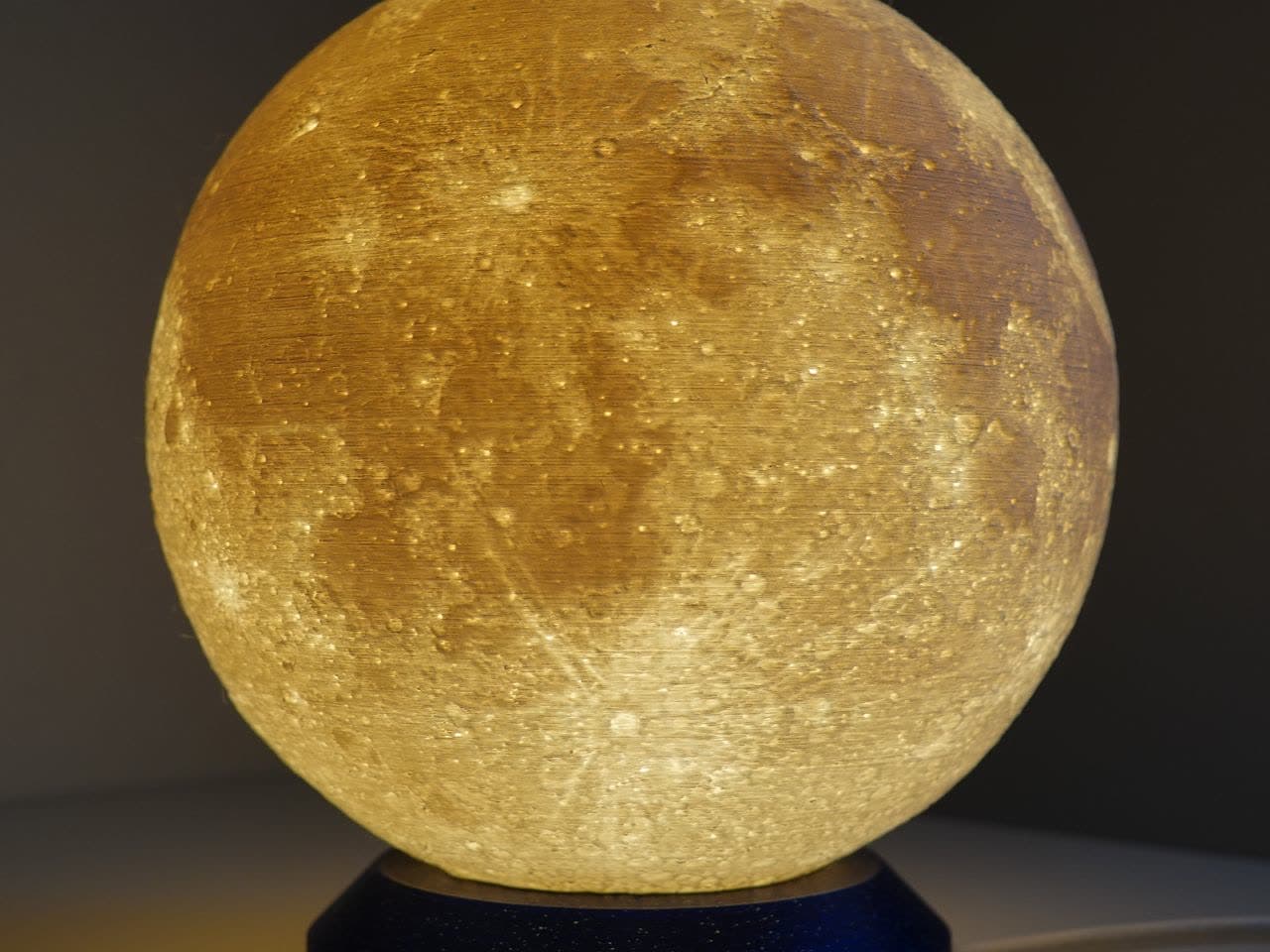 A moon lamp glowing from within on its base.