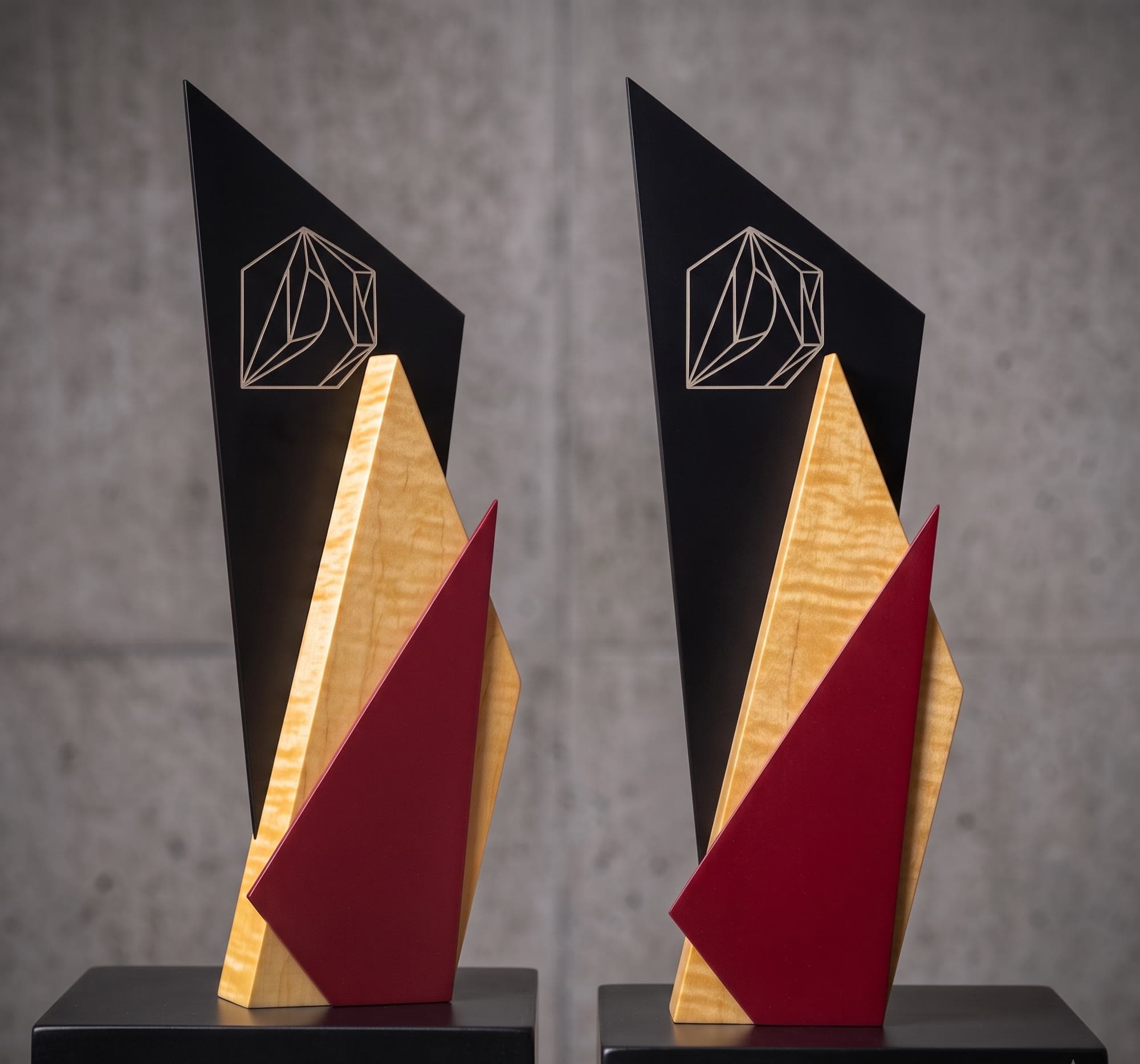 A pair of matching trophies in black metal, curly maple and burgundy, each engraved with the same mark.